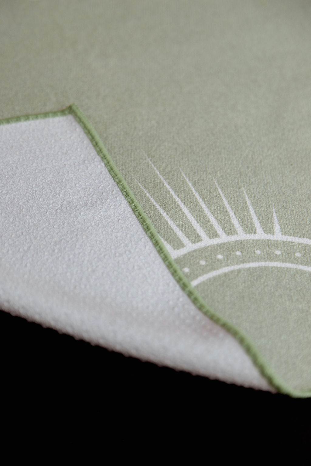 Close-up of a green and white non slip eco friendly hot yoga towel, showcasing 44% more silicone coverage in corner