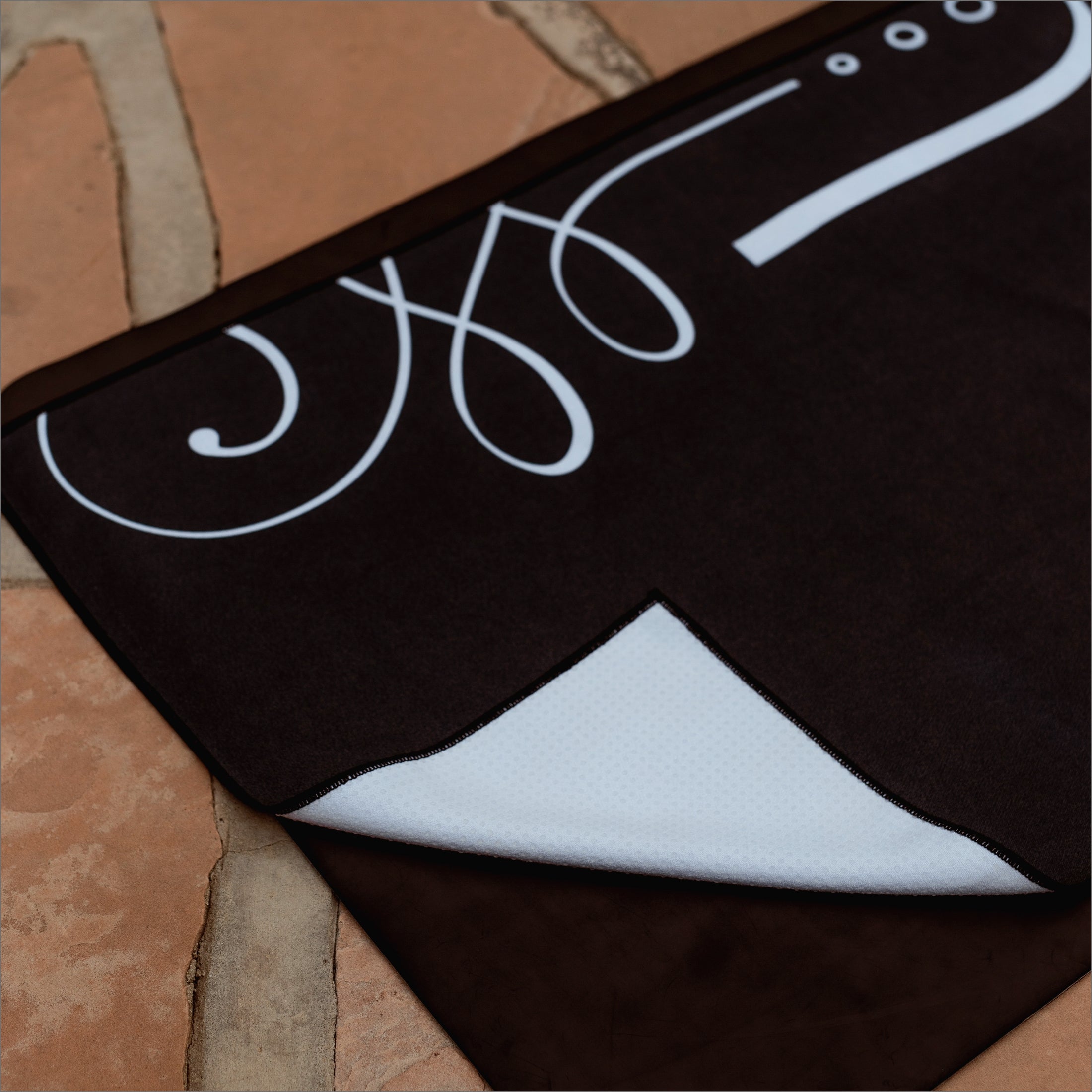 Non slip grip with 44% more silicone coverage on back of unalome yoga hot yoga towel. Black background and white minimal designs