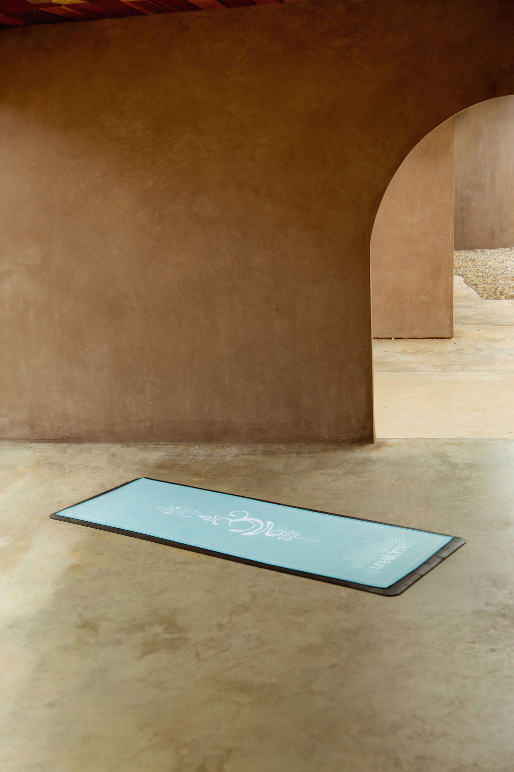 Light blue yoga towel on black yoga mat with text and om design